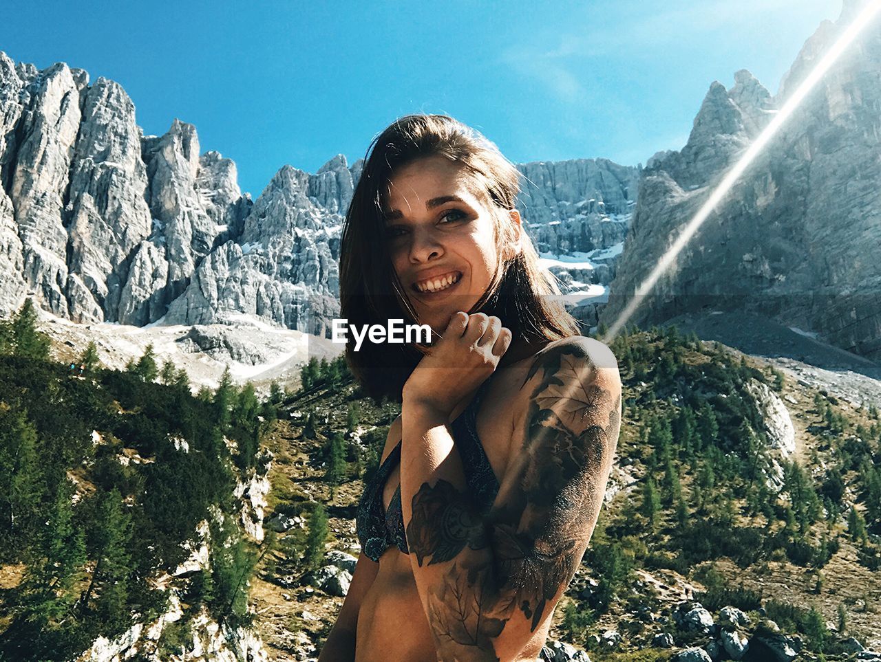 Portrait of young woman standing against mountains