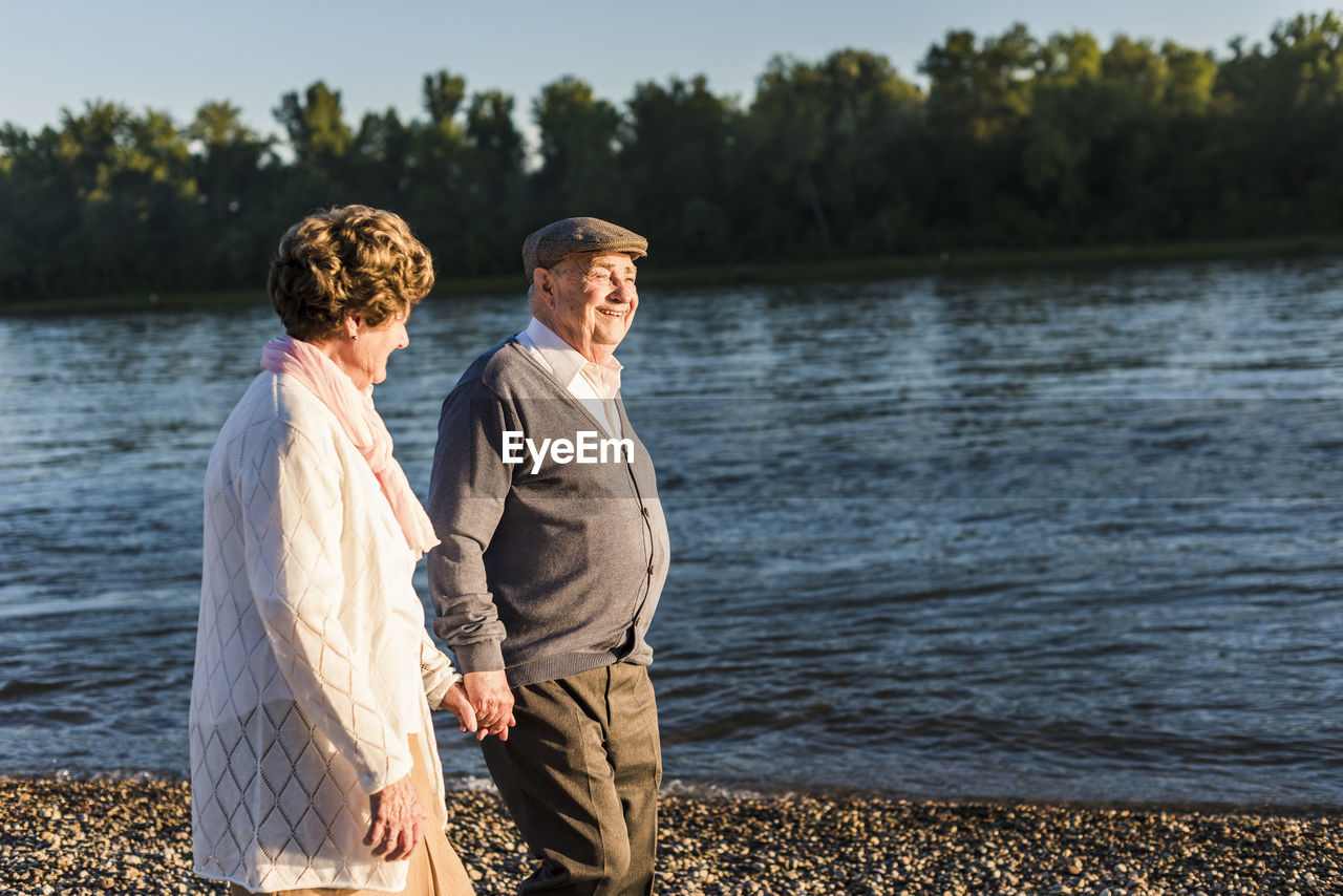 Happy senior couple walking hand in hand at riverside