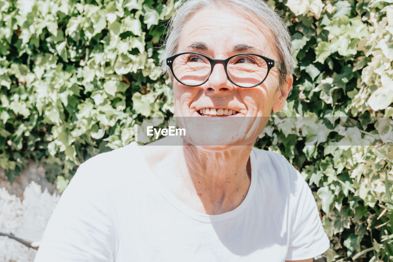 portrait of young man wearing eyeglasses against plants