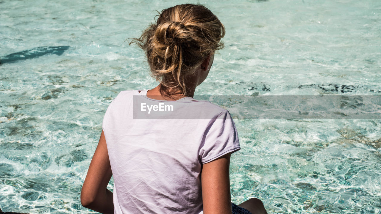 Rear view of woman sitting by sea