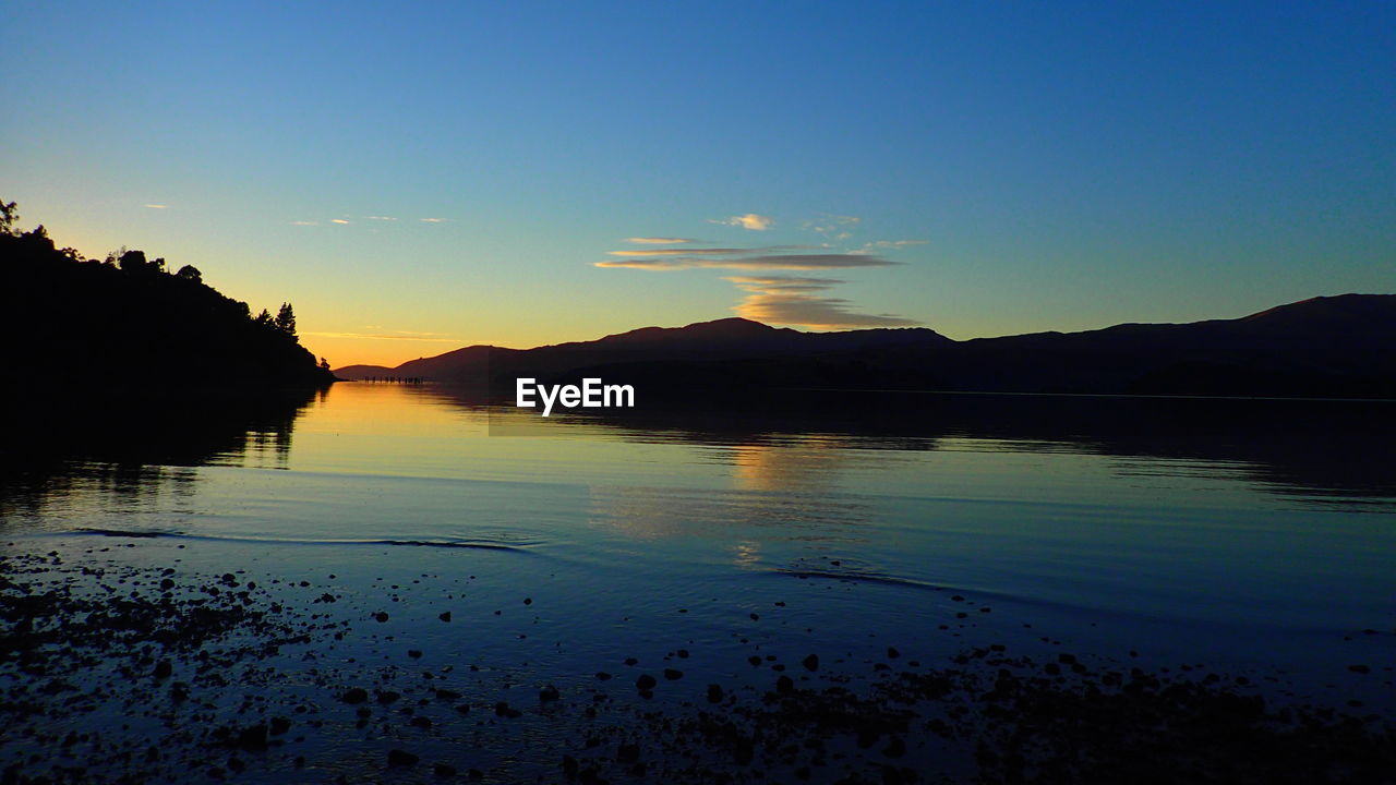 Scenic view of lake against clear sky during sunset