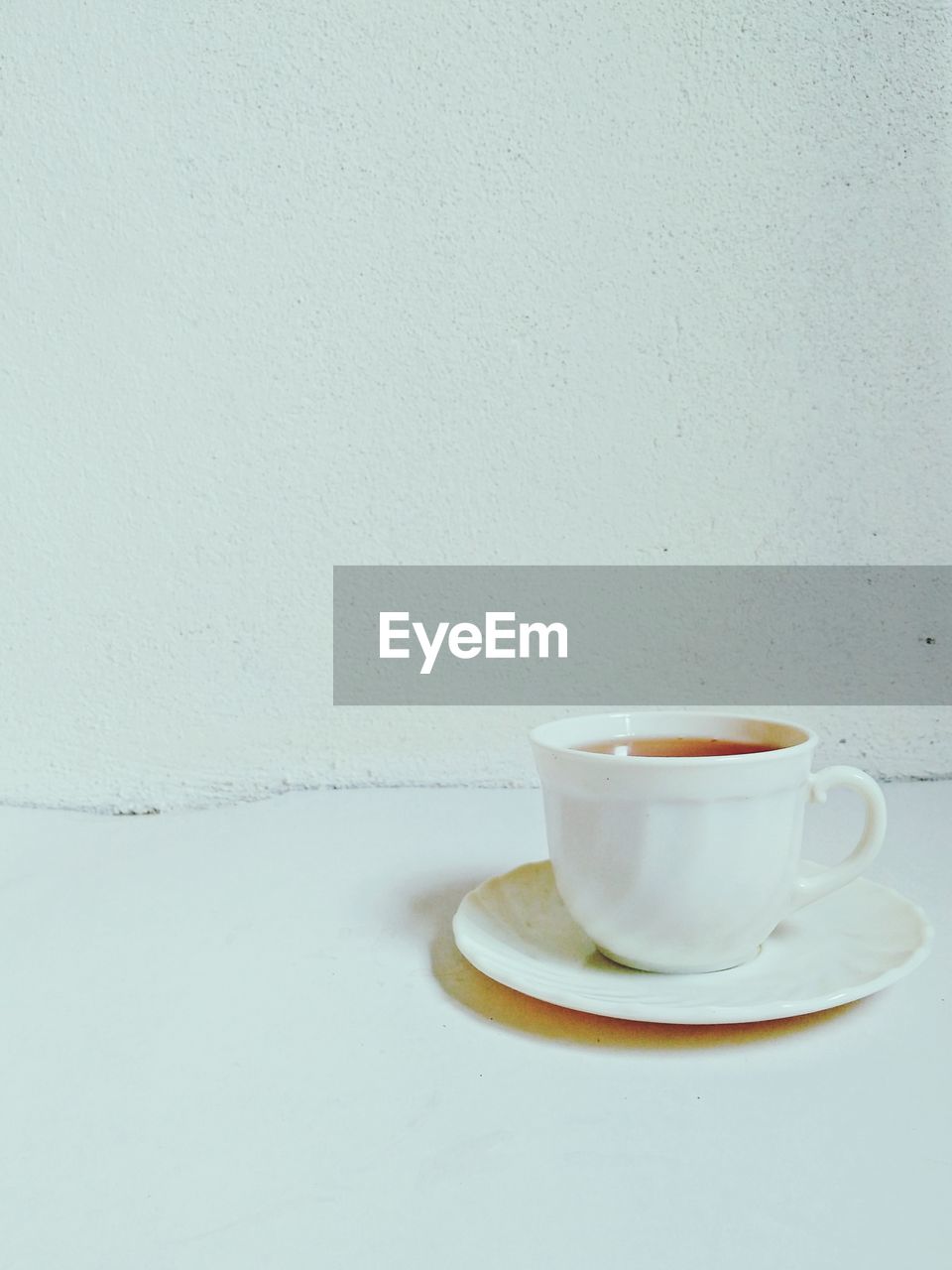 CLOSE-UP OF COFFEE CUP ON TABLE AGAINST GRAY BACKGROUND