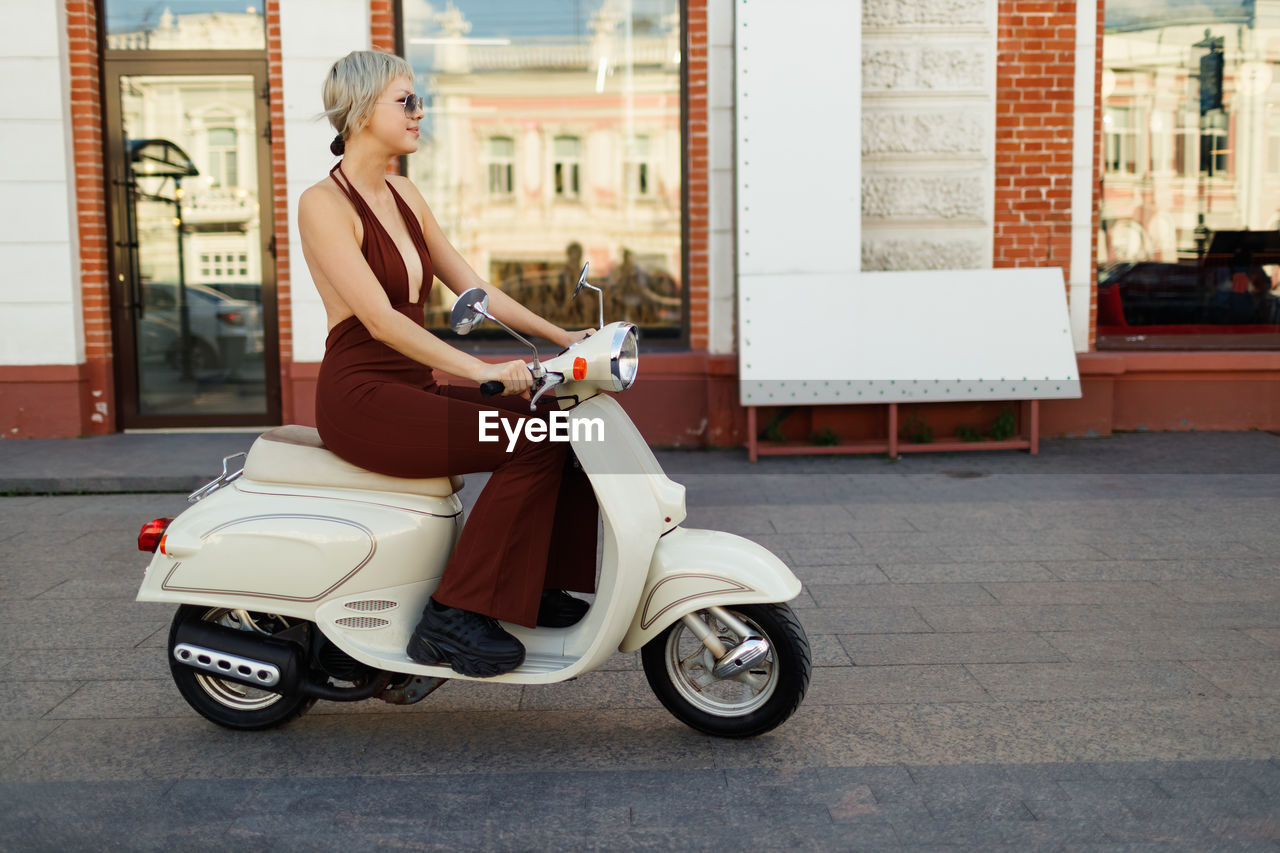 rear view of man riding motor scooter on street