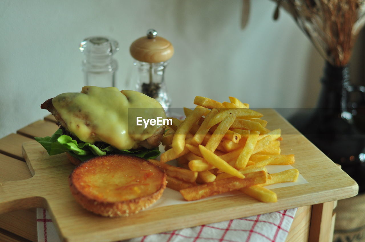 CLOSE-UP OF BURGER AND FRIES ON TABLE