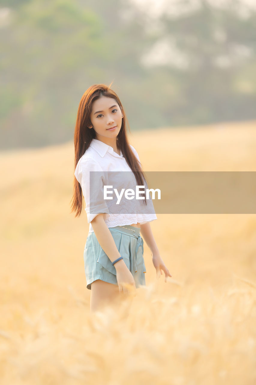 Portrait of smiling young woman standing on field