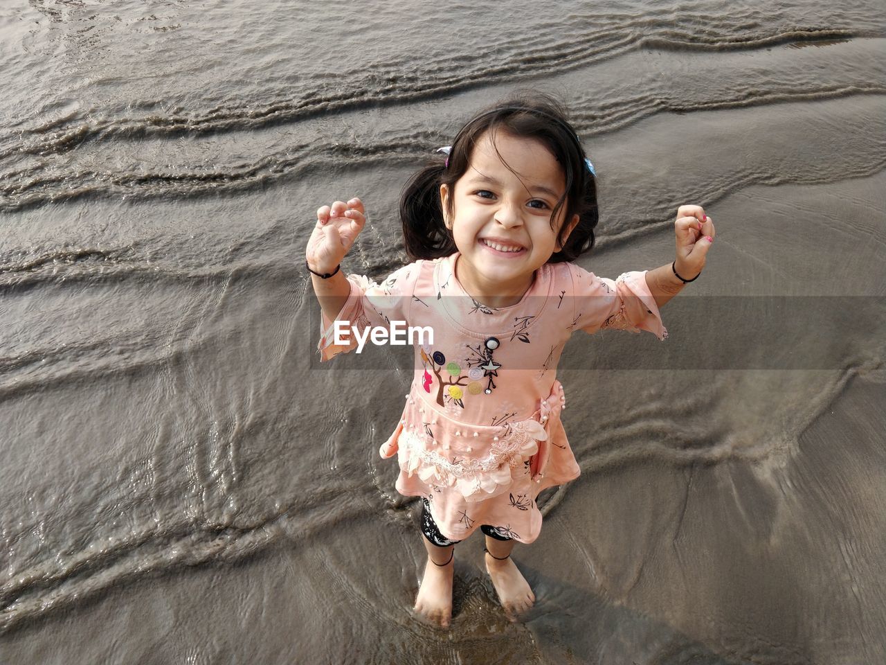 PORTRAIT OF A SMILING GIRL WITH ARMS OUTSTRETCHED