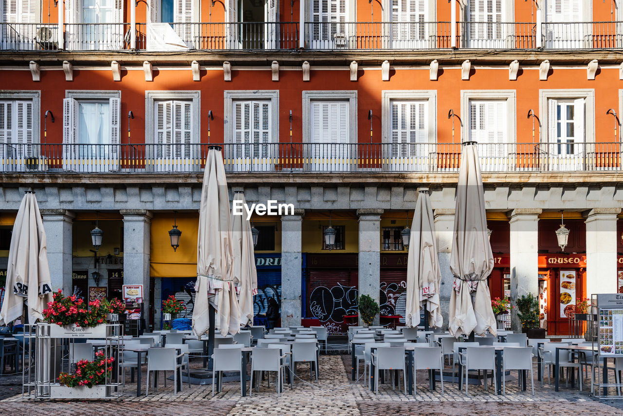 CHAIRS AND TABLES AT SIDEWALK CAFE AGAINST BUILDINGS