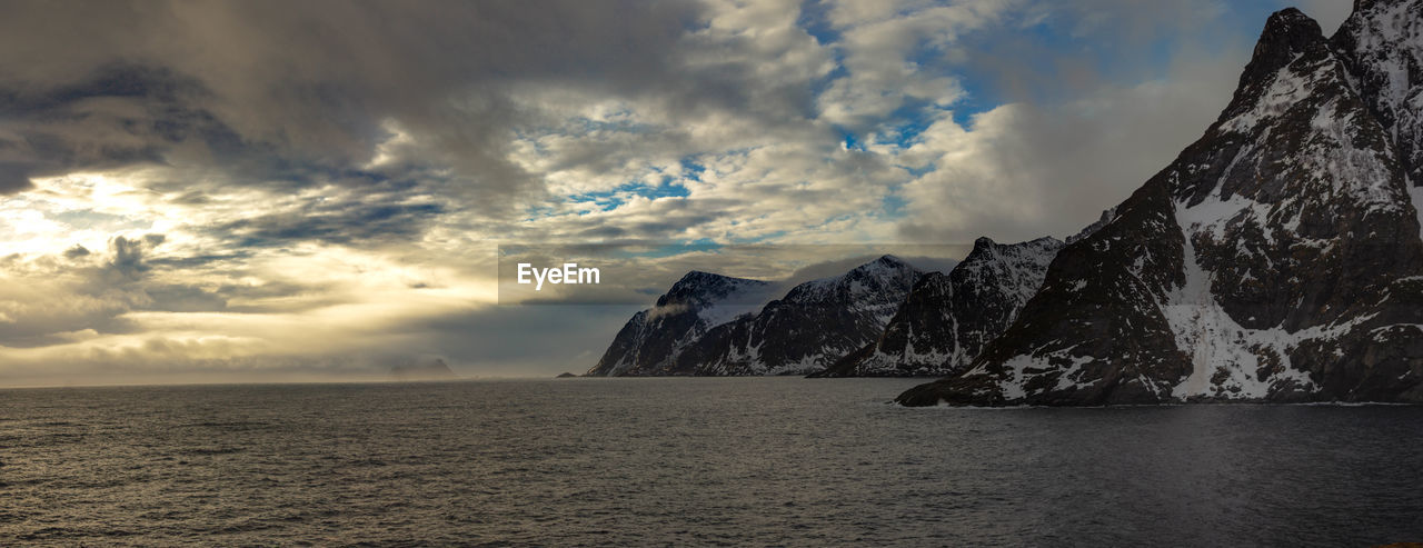 Scenic view of sea by snowcapped mountain against sky