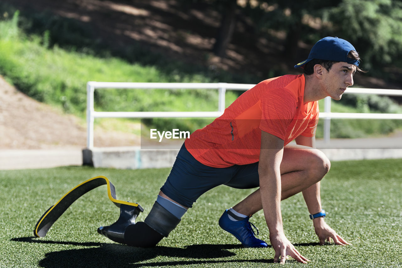 Side view of young athlete with prosthetic leg on running track