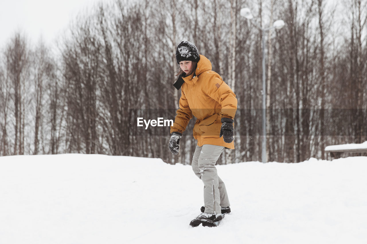 Cute teenage girl rides a snowskate in a winter park, healthy lifestyle