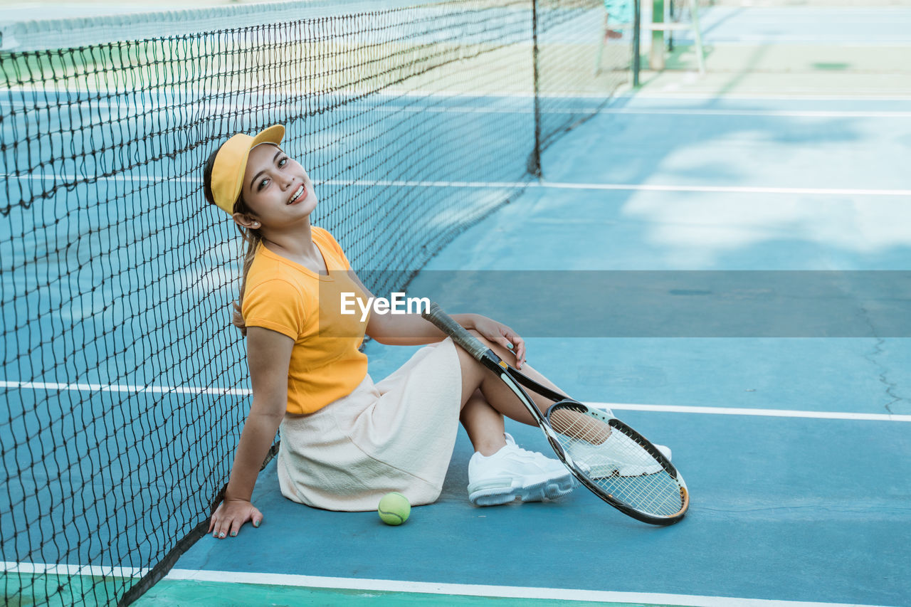 full length of young woman playing tennis