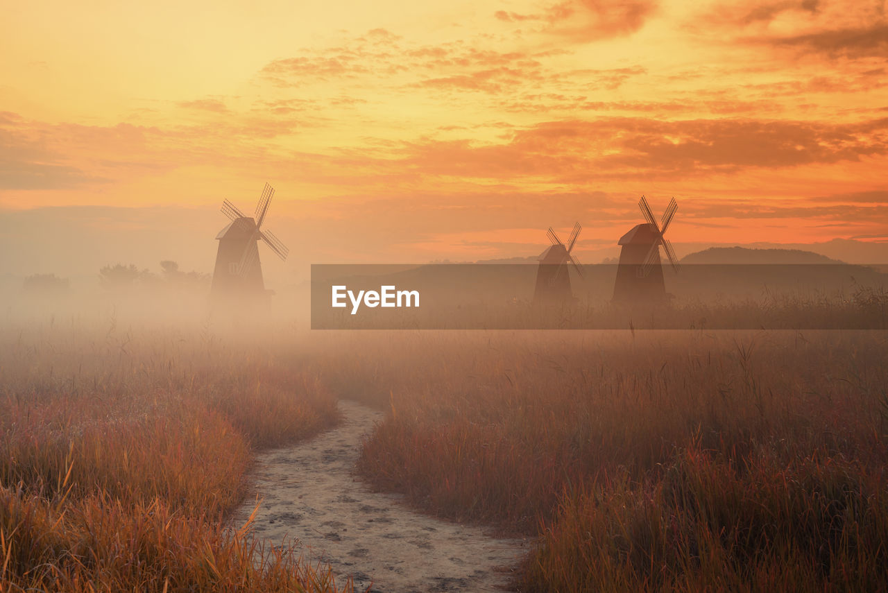 Scenic view of windmills against sky during sunset