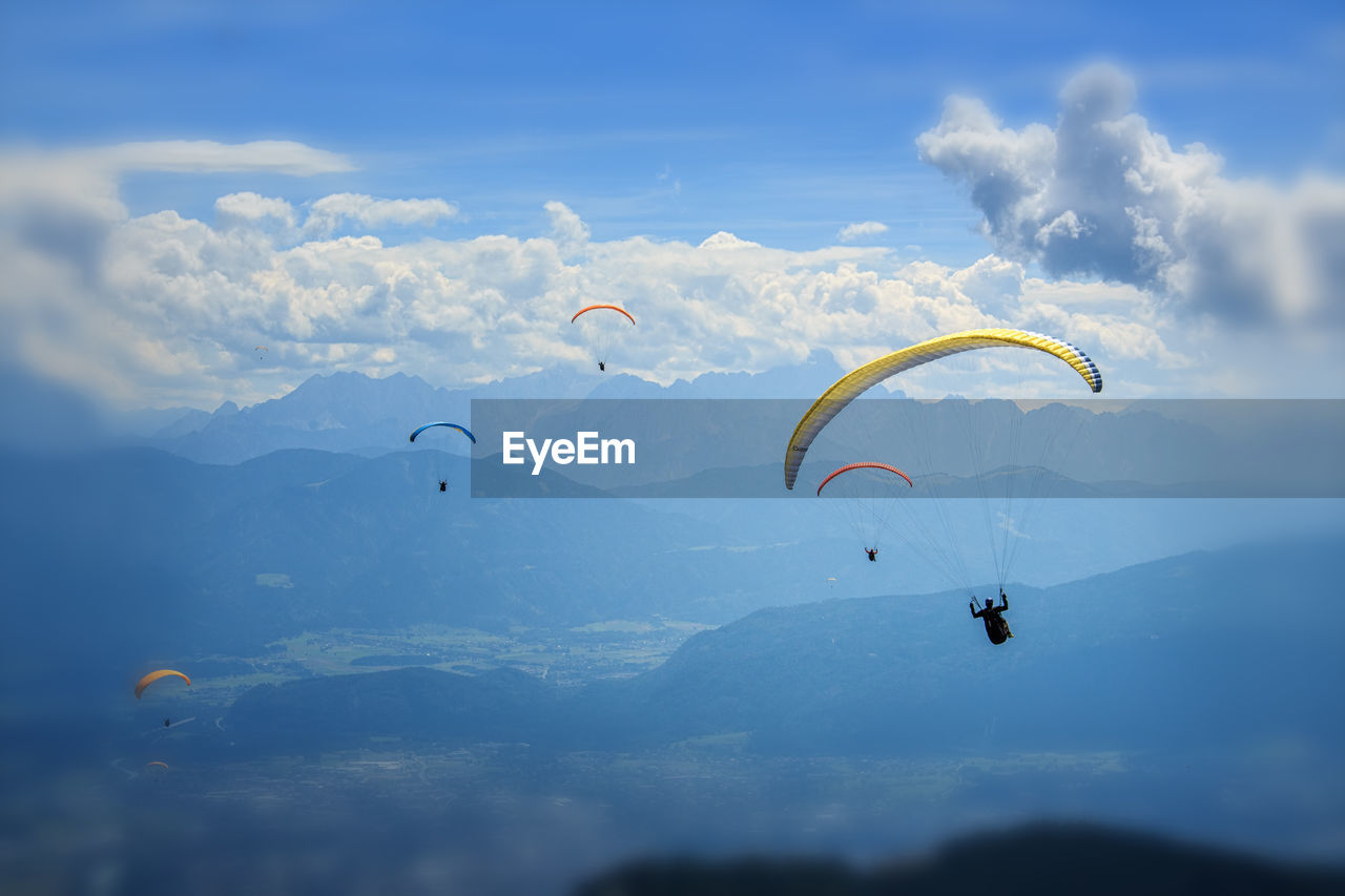 Low angle view of people paragliding against sky
