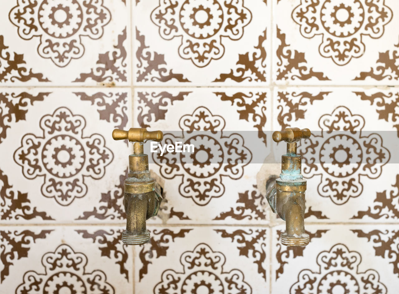 Close-up of faucets on tiled wall