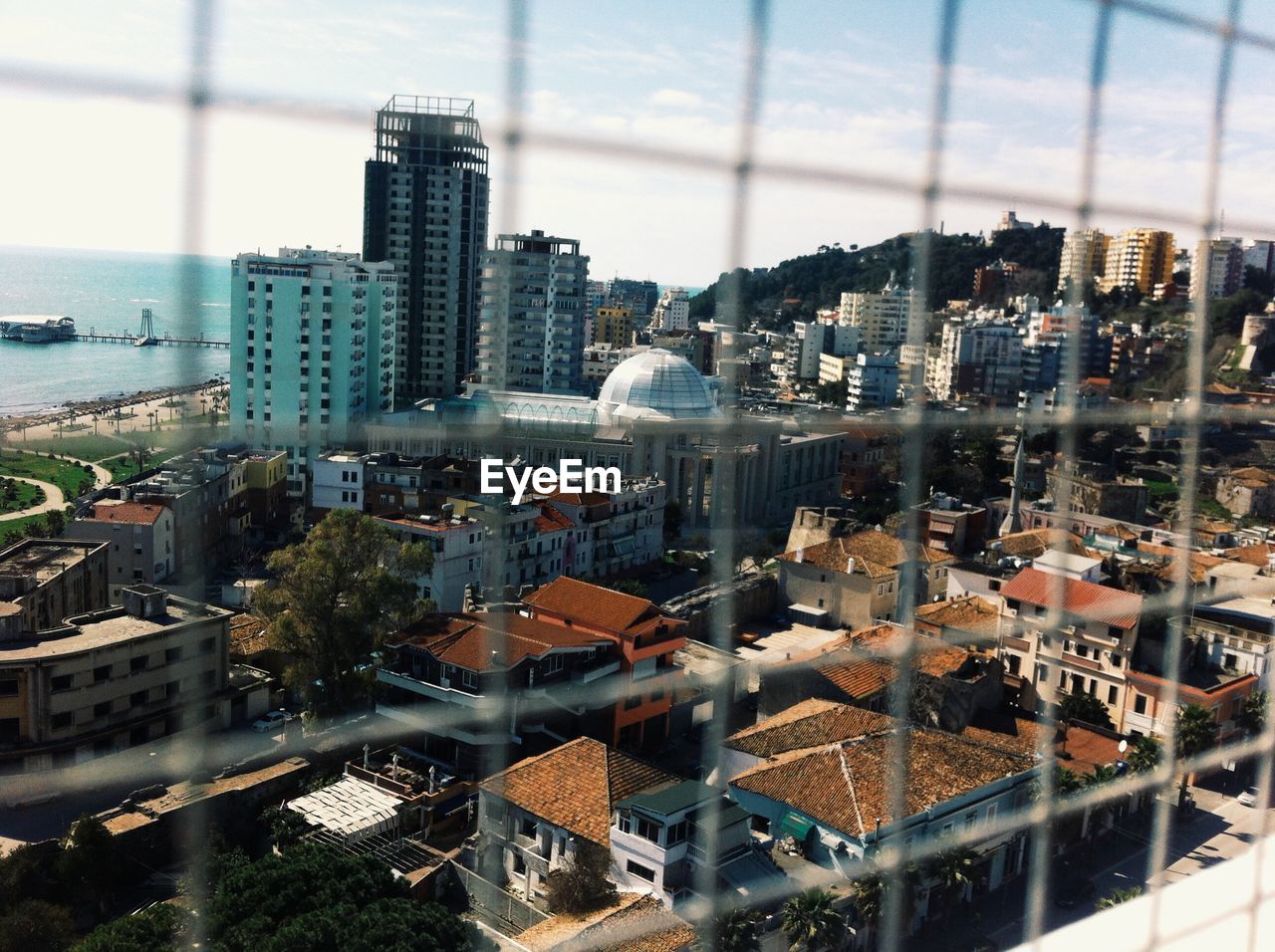 View of cityscape through chainlink fence