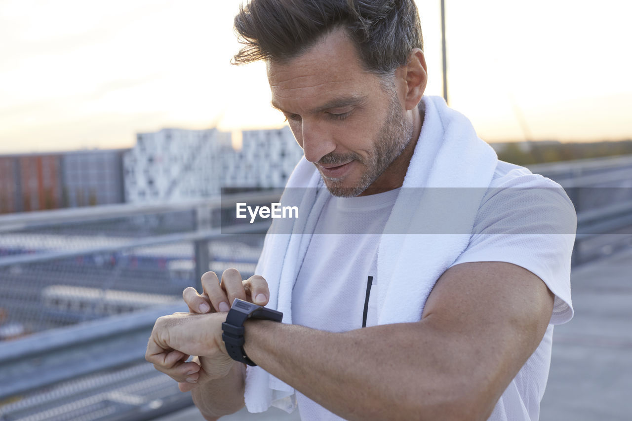 Athlete in the city looking on smartwatch