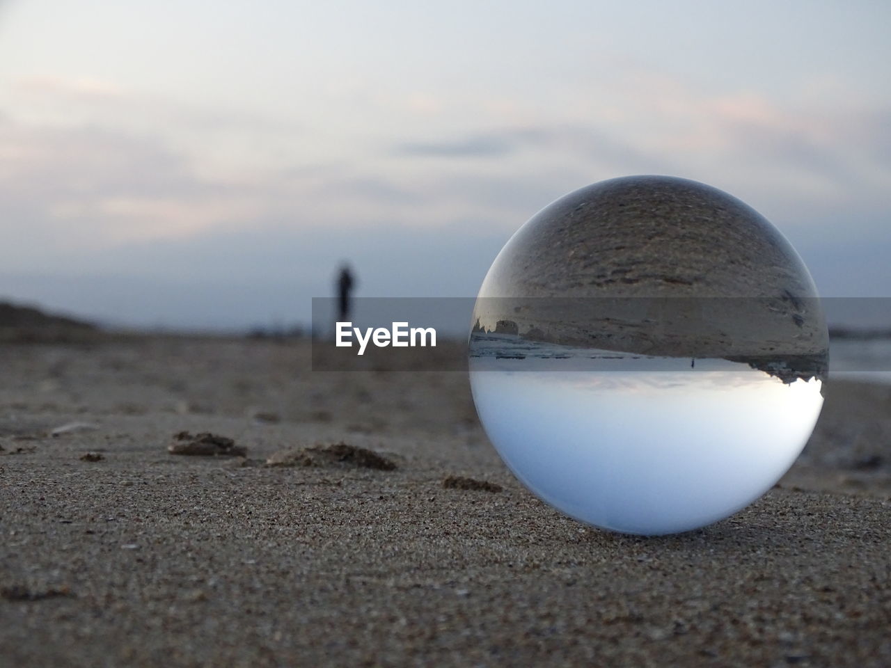 Close-up of crystal ball on beach against sky during sunset