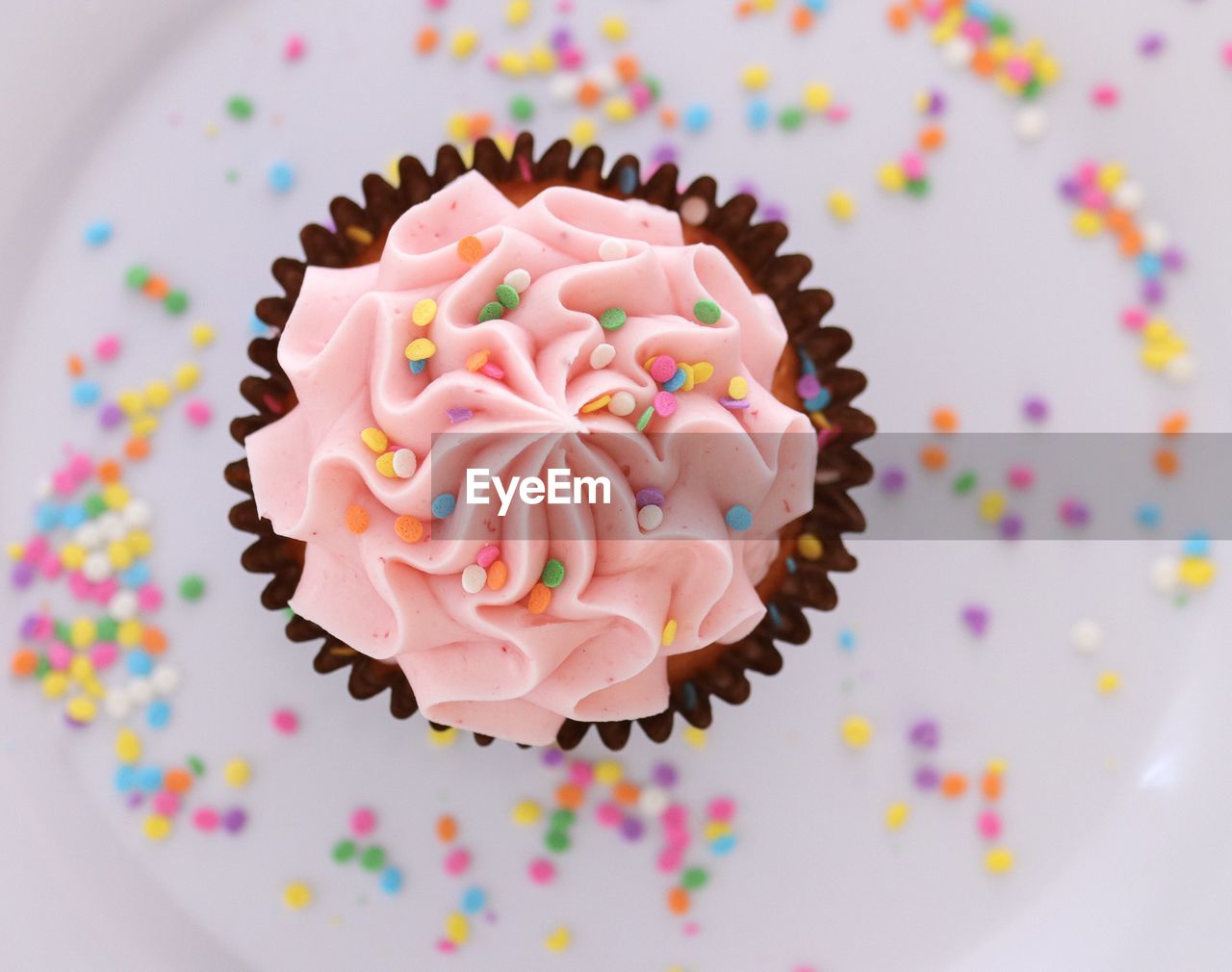 High angle top view of a pink cupcake with sprinkles