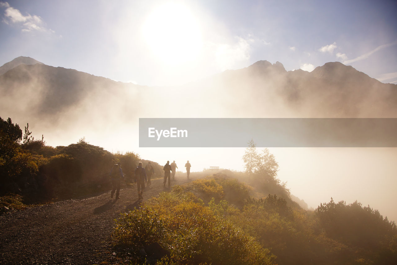 People walking on road against mountains during foggy weather at lechtal