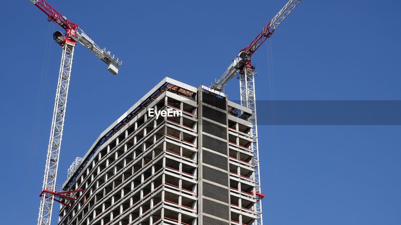 Low angle view of crane and building against clear sky