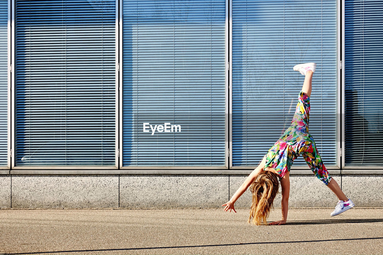 Upside down image of girl by wall outdoors