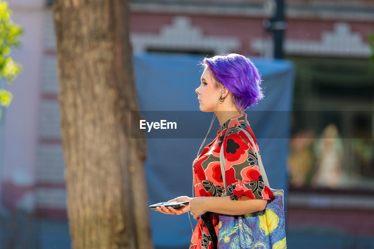 SIDE VIEW OF WOMAN LOOKING AT CAMERA OUTDOORS