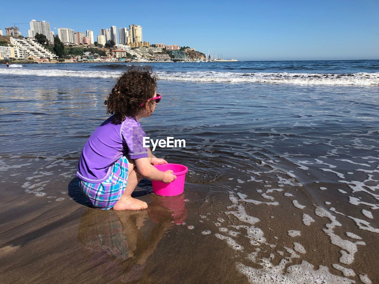Side view of girl with bucket playing at beach