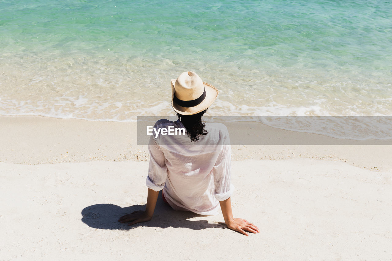 Rear view of woman sitting on the beach