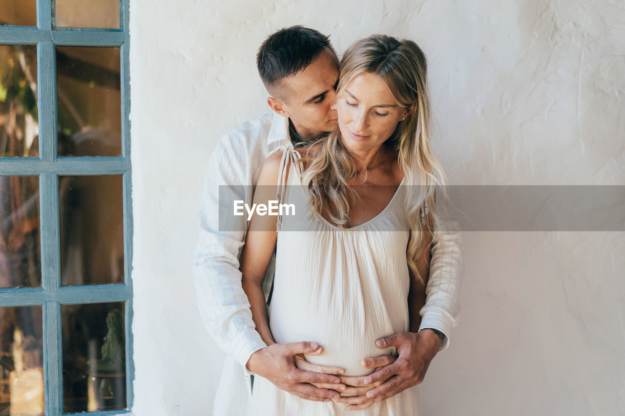 A man hugs a pregnant woman, a loving couple is expecting the birth of a baby.