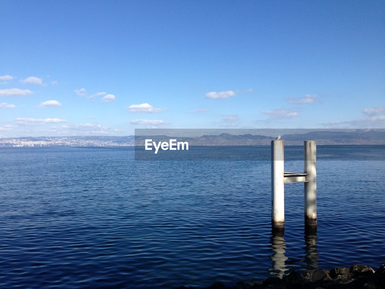 WOODEN POST IN SEA AGAINST SKY