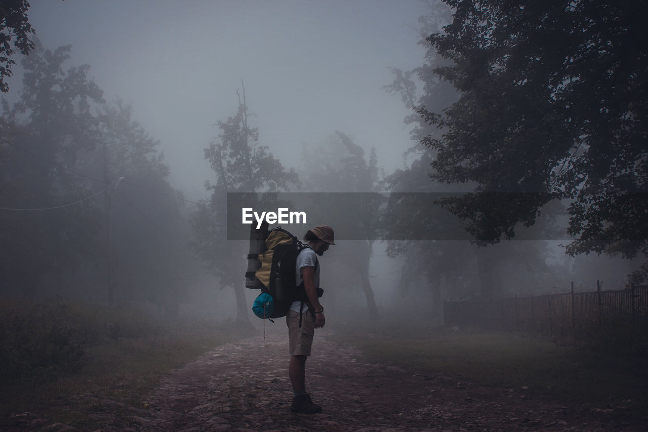 Side view of backpacker standing in forest