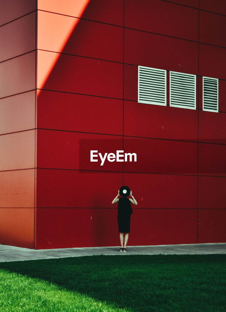 Full length rear view of woman standing against wall