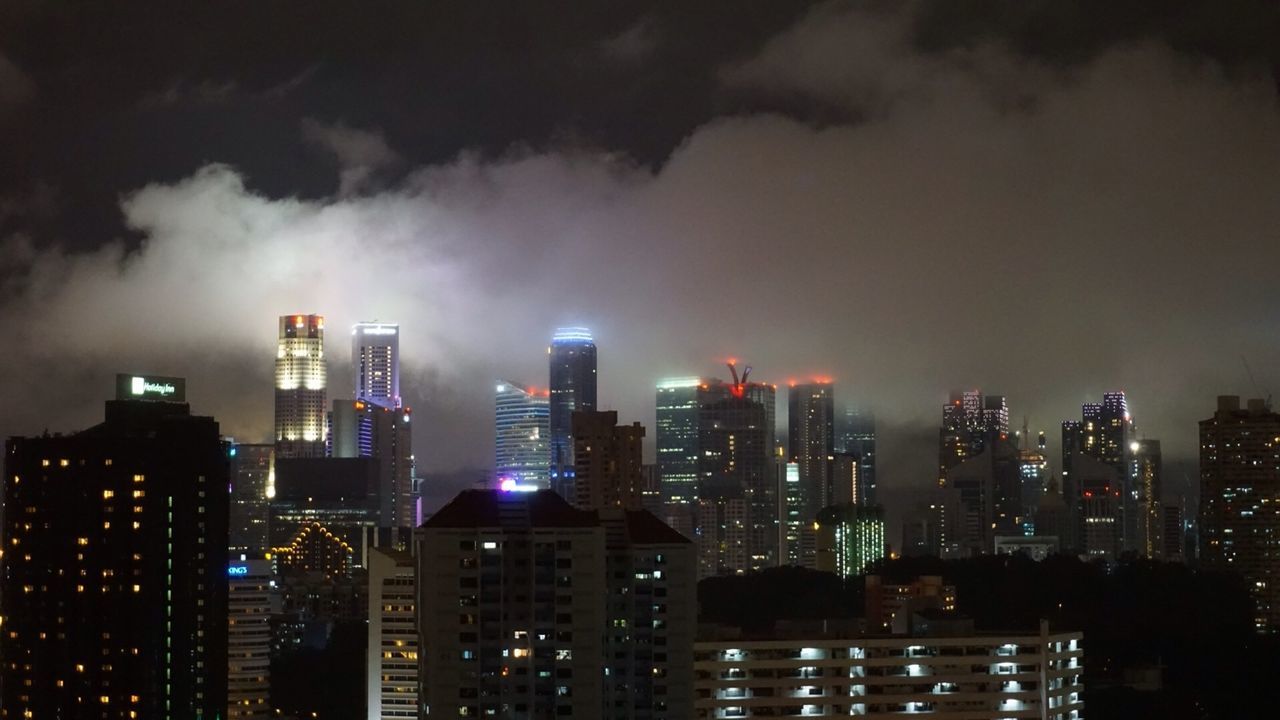 Illuminated cityscape against cloudy sky