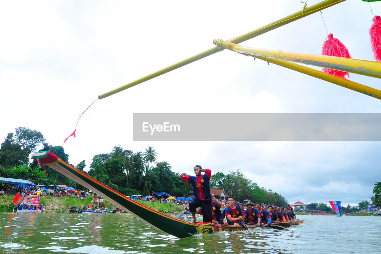 PEOPLE IN BOAT ON WATER AGAINST SKY