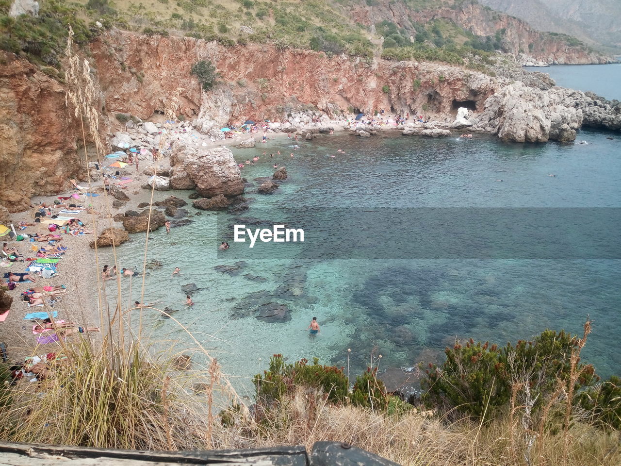 HIGH ANGLE VIEW OF ROCKS BY SEA AGAINST MOUNTAIN