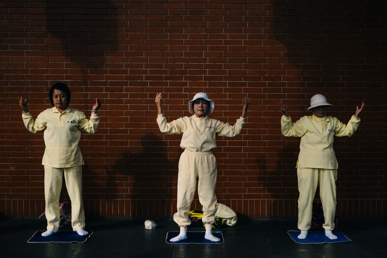 FULL LENGTH OF MEN STANDING ON BRICK WALL