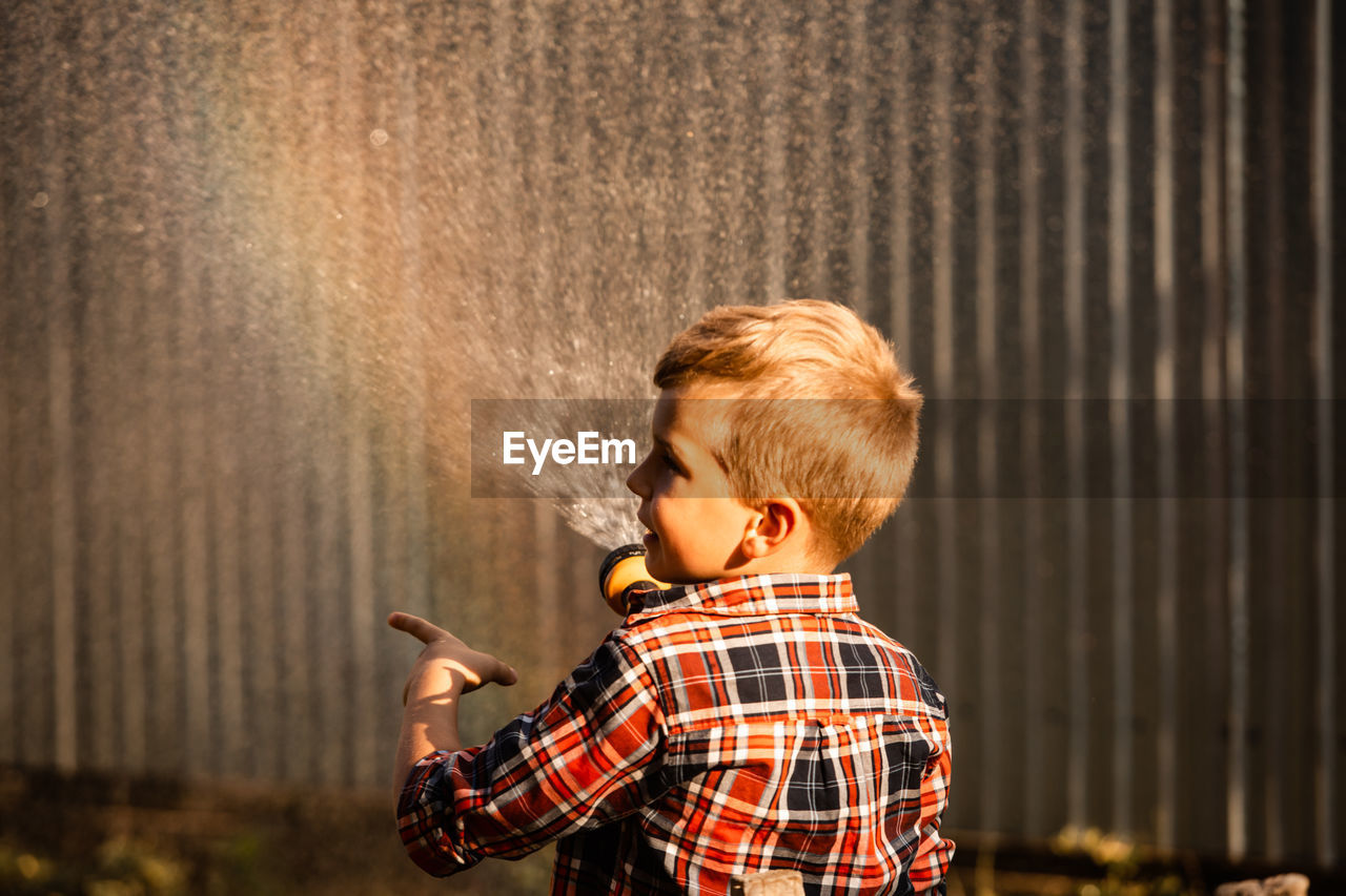 Side view portrait of boy standing against blurred background