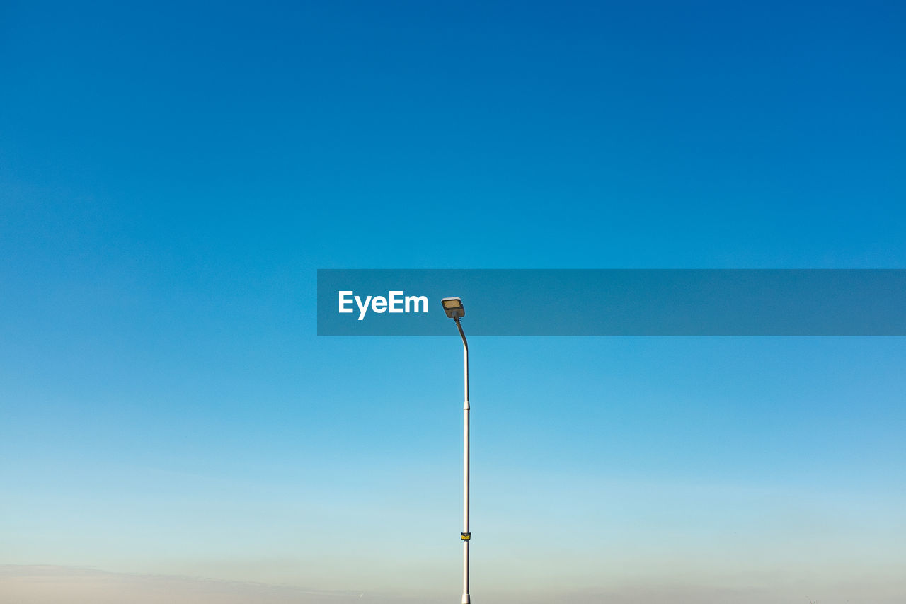 sky, blue, horizon, copy space, clear sky, nature, no people, scenics - nature, environment, beauty in nature, day, tranquility, wind, wind turbine, landscape, tranquil scene, outdoors, land, cloud, low angle view, street light, technology, sunny, sunlight, horizon over land