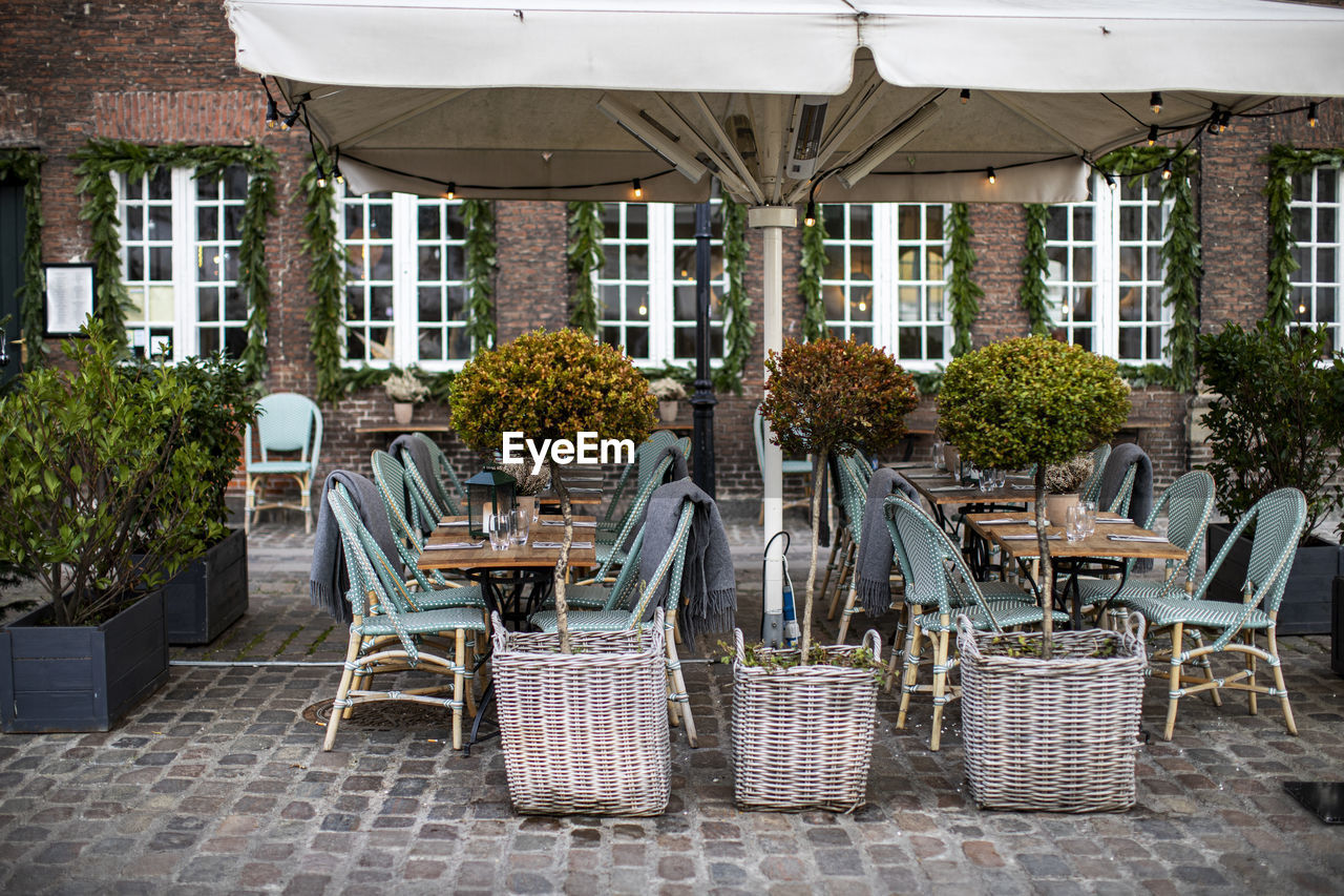 CHAIRS AND TABLES AT SIDEWALK CAFE AGAINST BUILDING