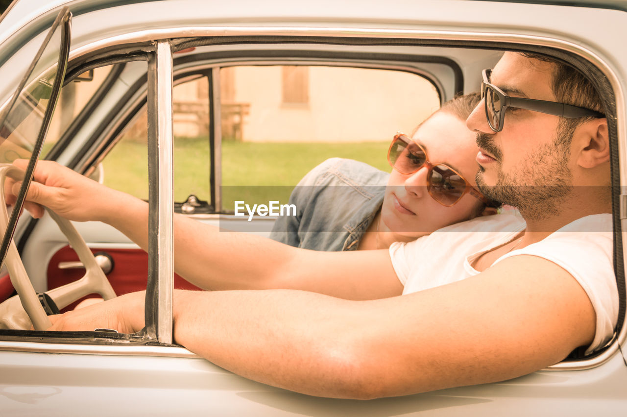Couple traveling in car seen through vintage car