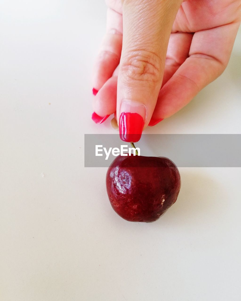 CLOSE-UP OF HAND HOLDING RED FRUIT