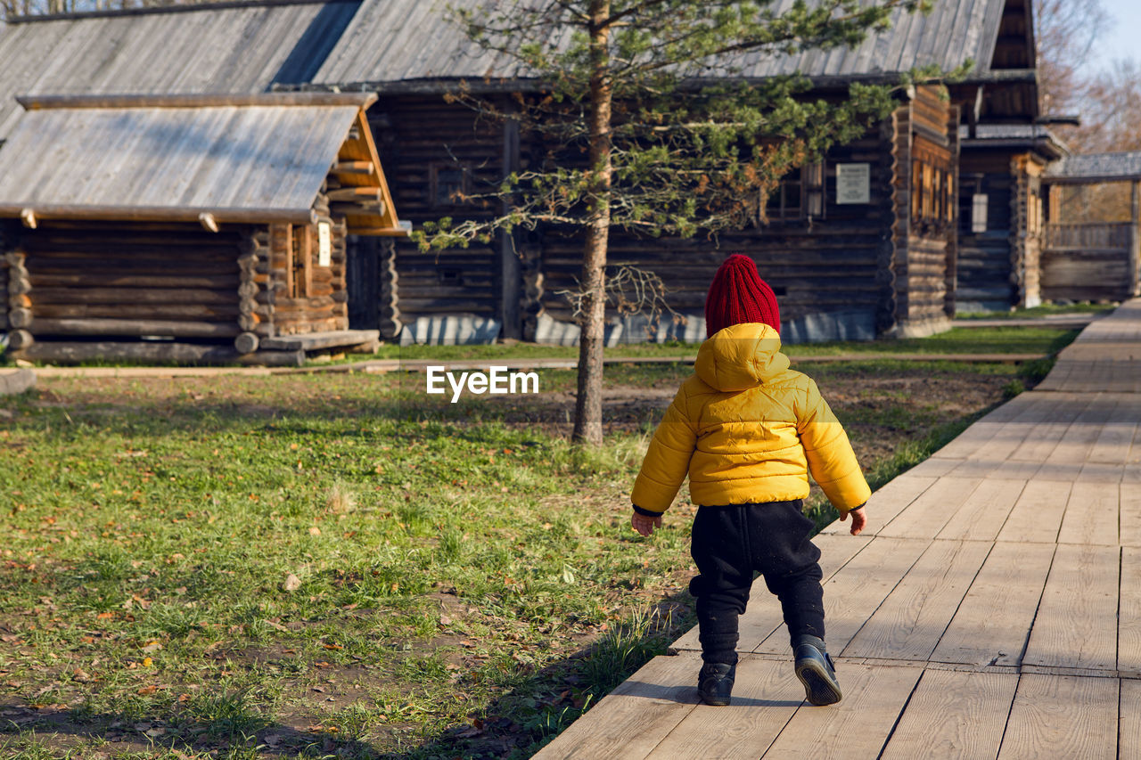 Boy in a yellow jacket walks in the village in the fall