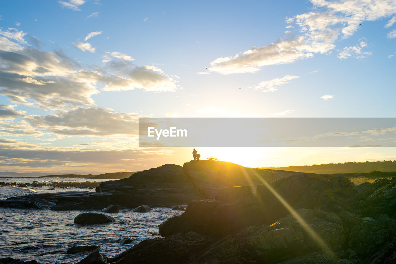 Scenic view of rocky sea shore against sky during sunset