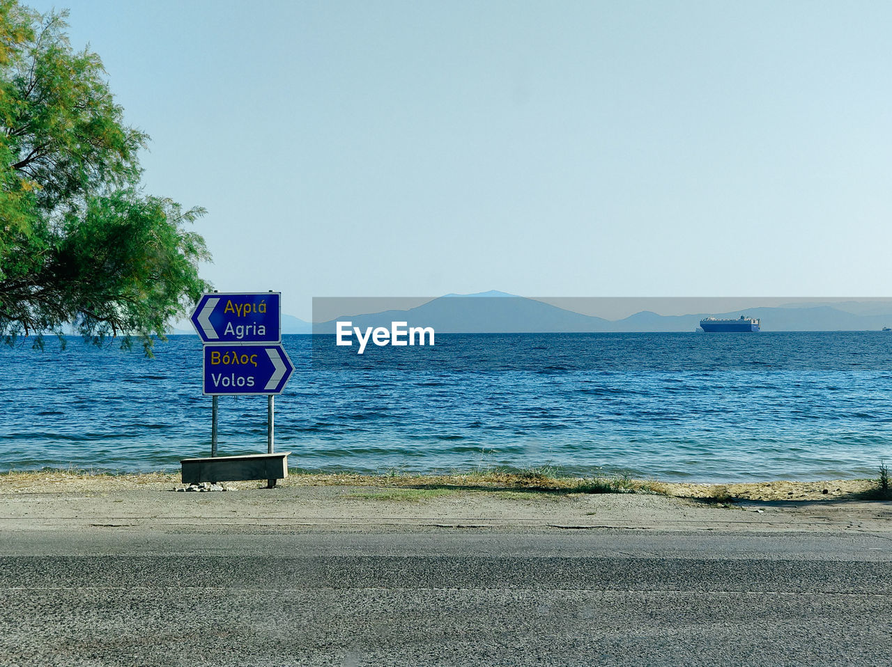 Road sign at beach against clear sky