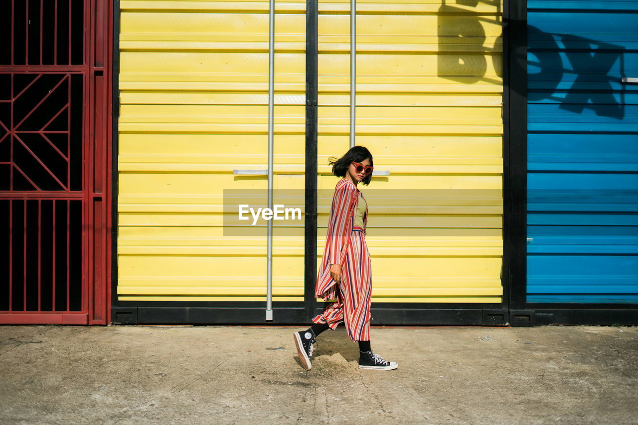 BOY STANDING AGAINST YELLOW SHUTTER