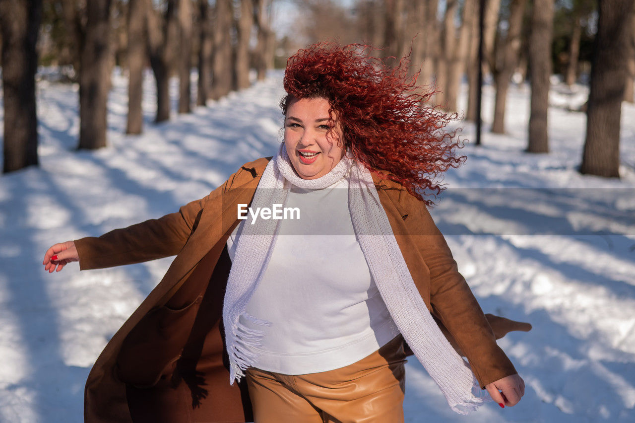 portrait of smiling young woman standing on snow covered field