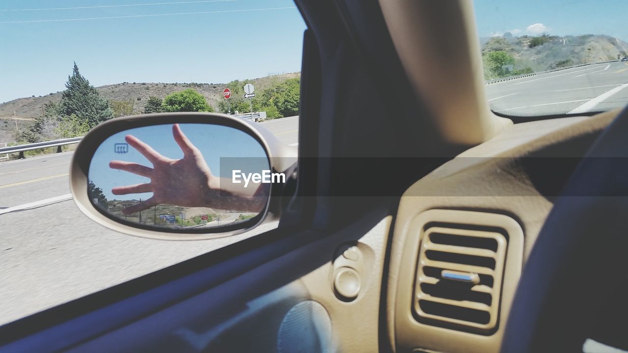 Reflection of hand on car side-view mirror