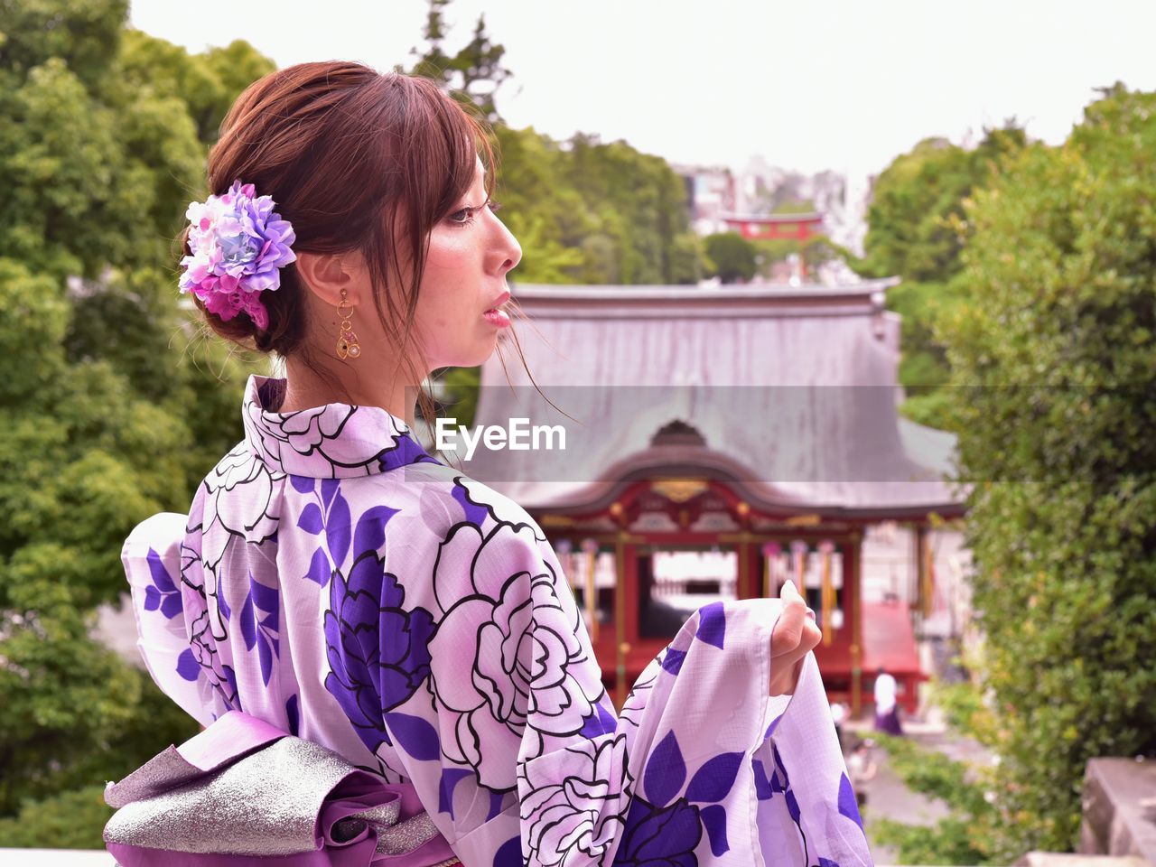 Young woman with purple flowers against plants