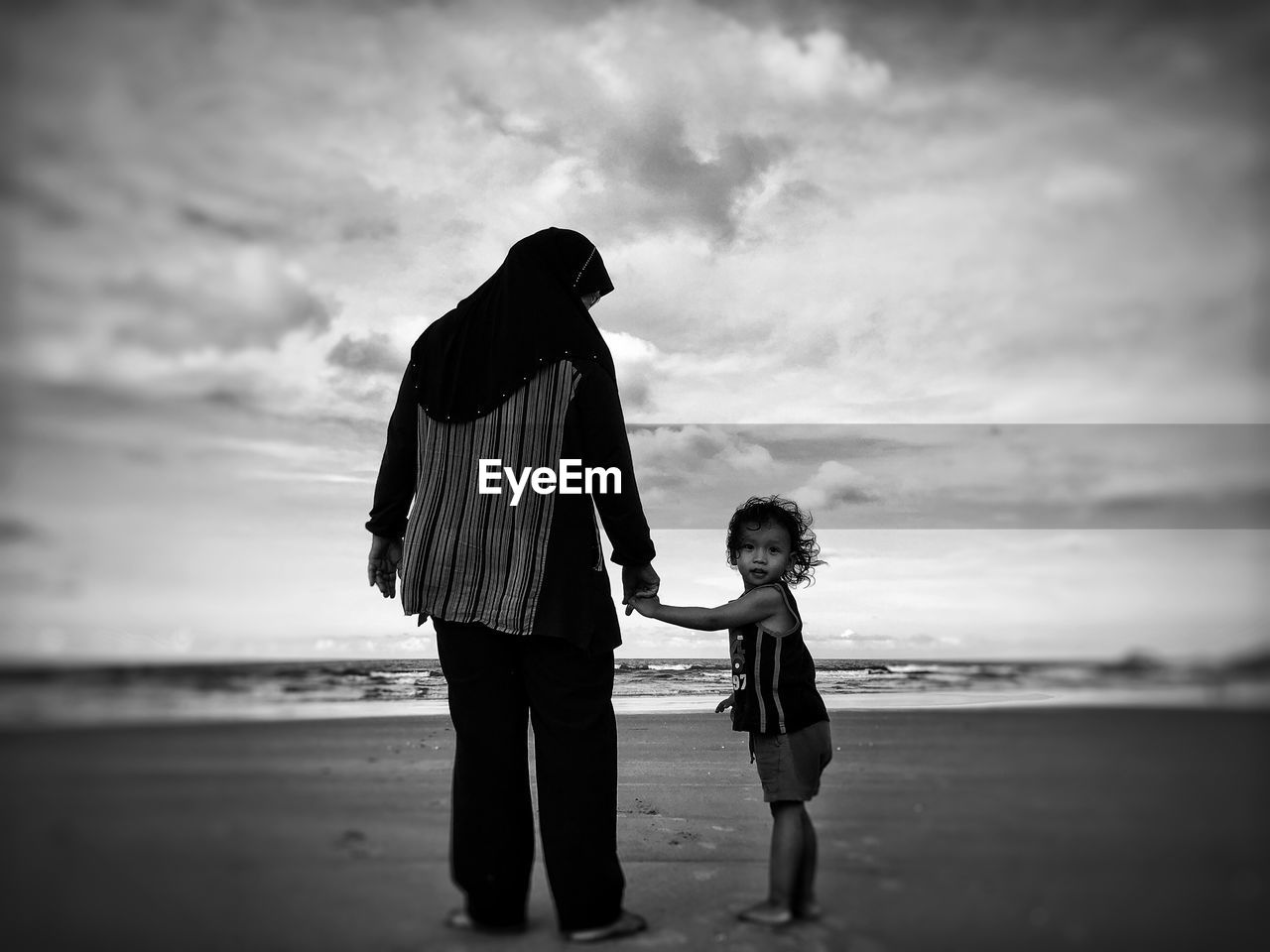 Portrait of girl with mother standing on shore at beach