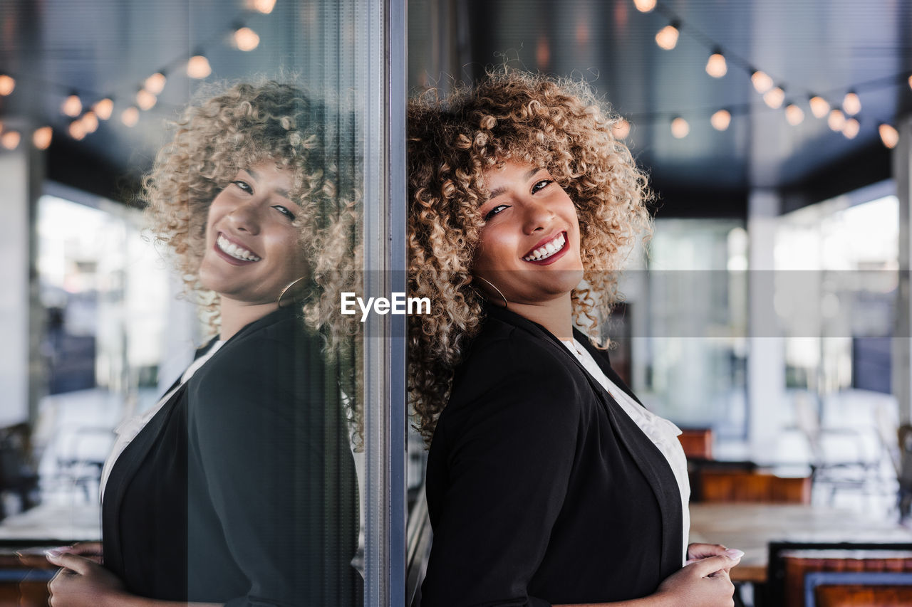 Portrait of beautiful smiling business woman leaning on glass in cafe. business concept
